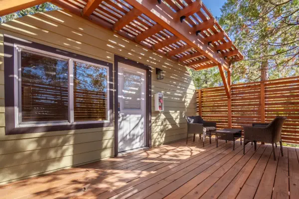 2 Bedroom Cabin at Tahquitz Pines Retreat, a sunny wood deck under a pergola with wicker seating by the cabin door