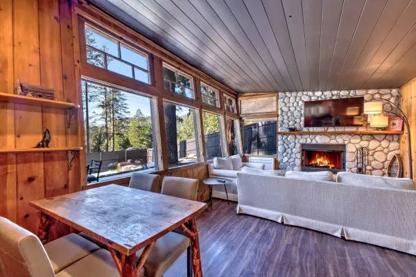 Cottage #63 at Tahquitz Pines Retreat, a living room with a lit stone fireplace, white sofas and walls of windows