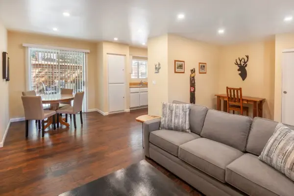 Cottage #76 at Tahquitz Pines Retreat, a living room with a gray sofa and a round dining table by a sliding door