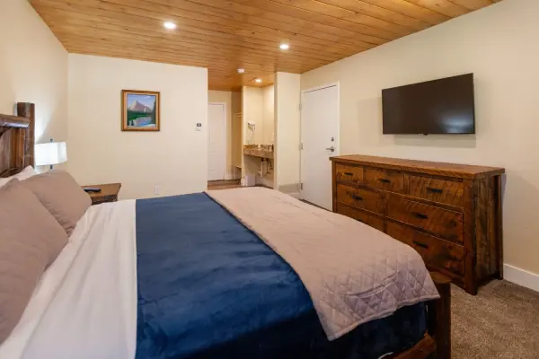 Economy King at Tahquitz Pines Retreat, a king bed with a log headboard facing a wall TV and rustic dresser