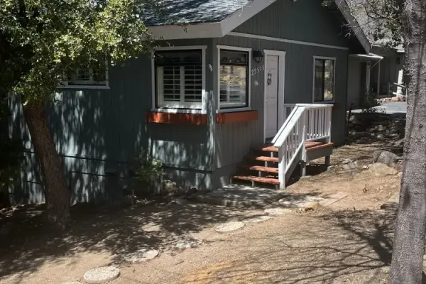 Lazy Bear at Tahquitz Pines Retreat, a gray-blue cottage with white porch steps beneath shady trees