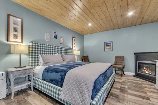 Manzanita at Strawberry Creek Inn, a king bed with a green gingham headboard and a lit fireplace against pale blue walls