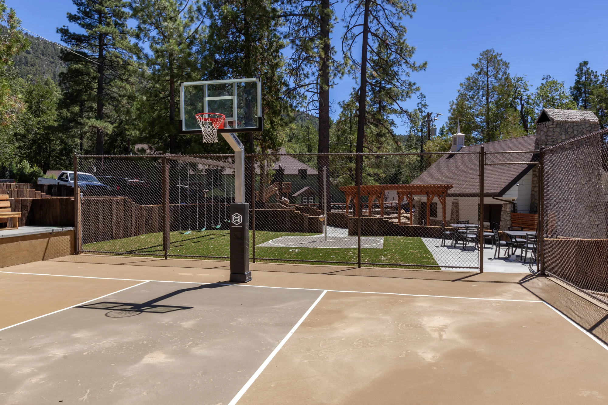 The basketball court at Tahquitz Pines Retreat, with swings, a lawn and the pergola patio beyond