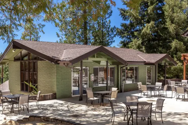 The green hall at Tahquitz Pines Retreat with its patio tables set under the pines