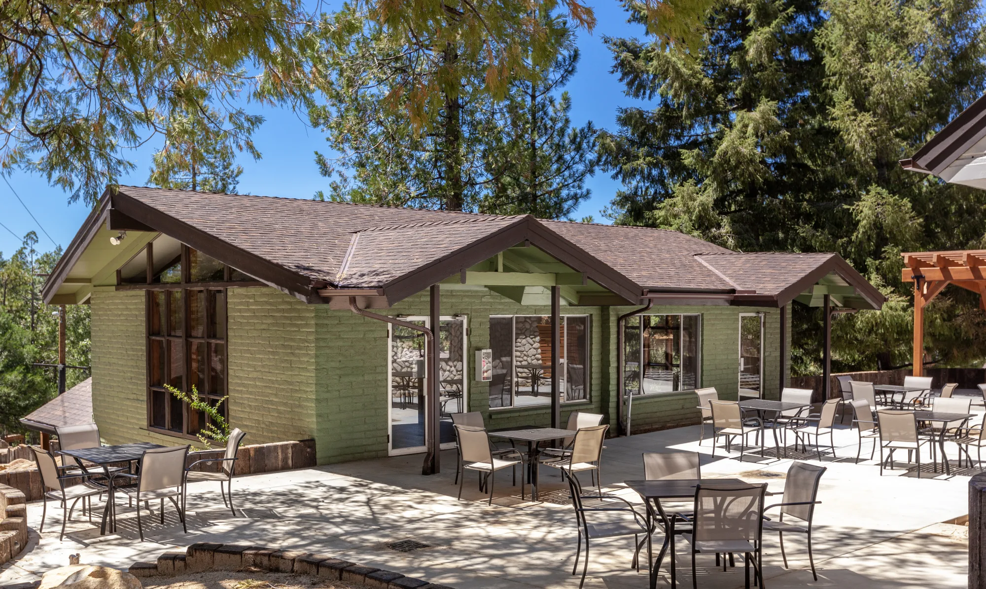 The green hall at Tahquitz Pines Retreat with its patio tables set under the pines