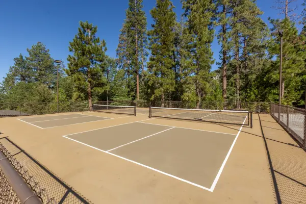 The pickleball court at Tahquitz Pines Retreat under a clear sky, pines behind the fence