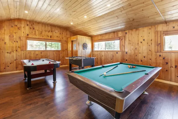 A pool table, air hockey table, foosball table and dartboard in the pine-paneled rec room at Tahquitz Pines Retreat