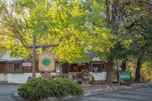 The carved Idyllwild Inn sign under golden trees at the front of the inn
