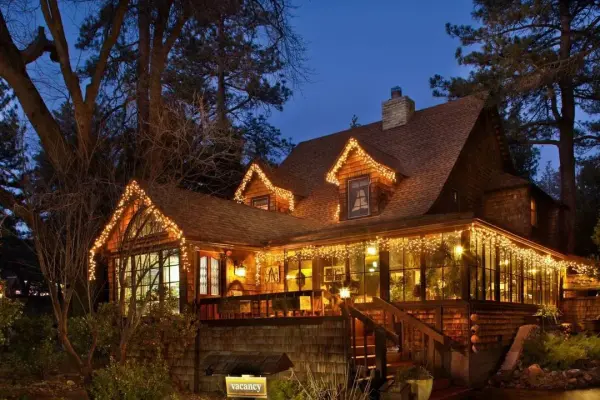 Strawberry Creek Inn at dusk, its shingled roofline strung with warm lights under the pines