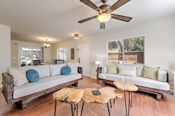 A living room in cabin 64 at Tahquitz Pines Retreat with two long sofas, live-edge tables and a dining table by the patio doors
