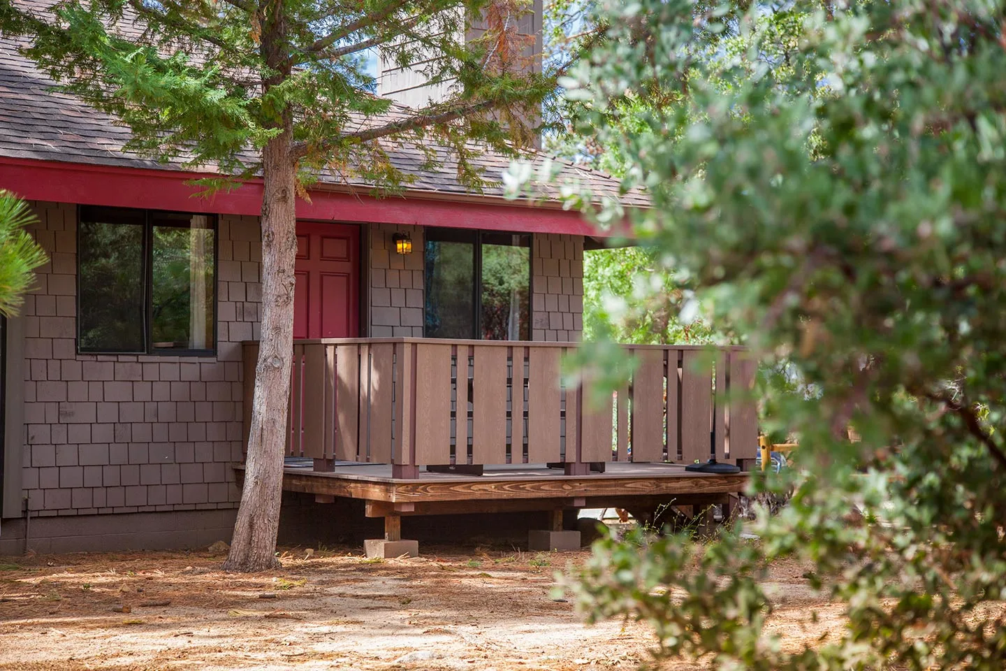A rustic wood cabin at Idyllwild Inn under the pines, with a porch and a stone chimney