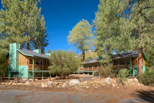 Theme Room, Queen at Idyllwild Inn, two-story lodge buildings with teal trim and balconies beneath tall pines