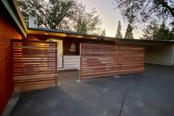 Theme Room Suites at Idyllwild Inn, a low building entry behind horizontal cedar slat screens at dusk